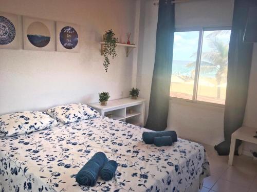 een slaapkamer met een bed met blauwe kussens en een raam bij OceanFront Flat I by Canary365 in Las Palmas de Gran Canaria