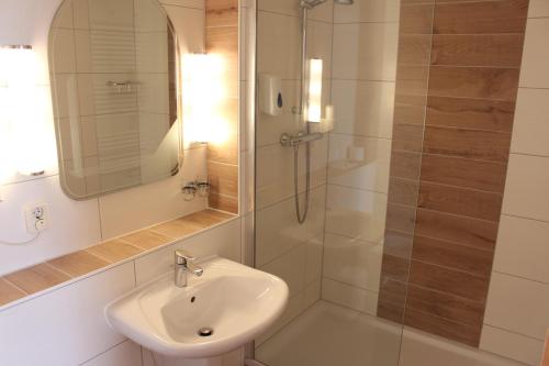 a white bathroom with a sink and a shower at Pension Zur Grünen Eiche in Kaulsdorf