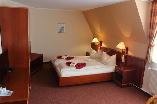 una camera d'albergo con un letto con due animali di peluche di Pension Zur Grünen Eiche a Kaulsdorf