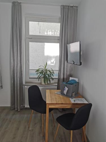 a desk and two chairs in a room with a window at Gästehaus Twee Linden in Warnemünde