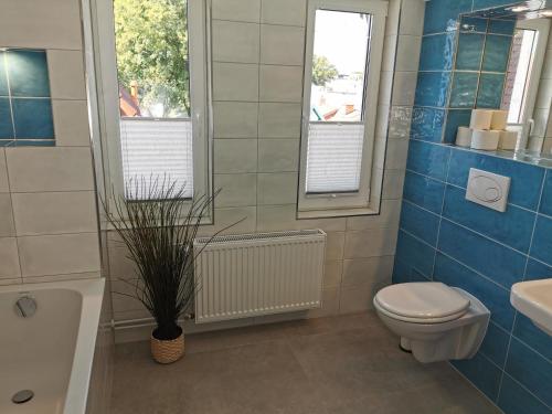 a blue tiled bathroom with a toilet and a sink at Gästehaus Twee Linden in Warnemünde