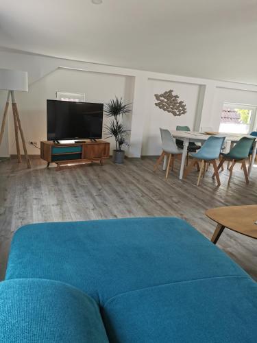 a living room with a blue couch and a tv at Gästehaus Twee Linden in Warnemünde