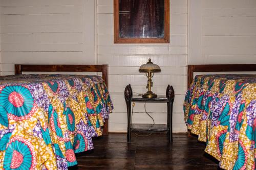 a room with two beds and a table with a lamp at Pousada Vila Paraíso in Santa Cruz