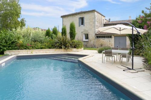 una piscina con mesa y sillas junto a una casa en le clos de Tesson, en Tesson