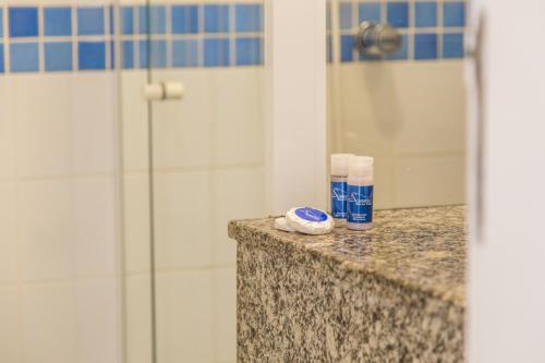 Un mostrador de baño con ducha y una botella de pasta de dientes. en Spazio Marine Hotel - Guaratuba, en Guaratuba