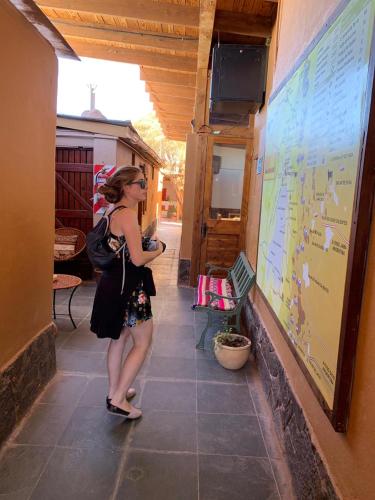 a woman standing in front of a map on a wall at Hostal Nuevo Amanecer in San Pedro de Atacama