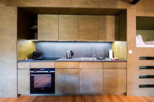 a kitchen with wooden cabinets and a sink and a stove at Kuglerhof Appartements in Seeboden