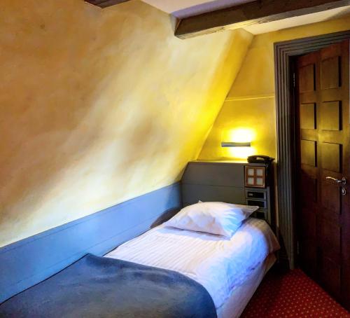 a small bed in a room with a yellow wall at Maison Kammerzell - Hotel & Restaurant in Strasbourg