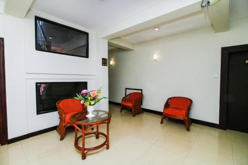 a waiting room with red chairs and a table with flowers at Omega Regency Colombo in Colombo
