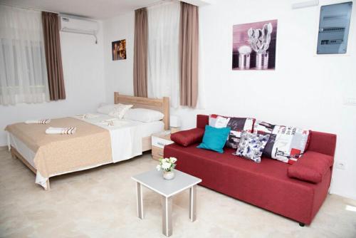 a living room with a bed and a red couch at Apartments Nino Skadar lake in Virpazar