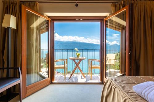a bedroom with a balcony with a view of the ocean at Hotel Meandro - Lake View in Gargnano