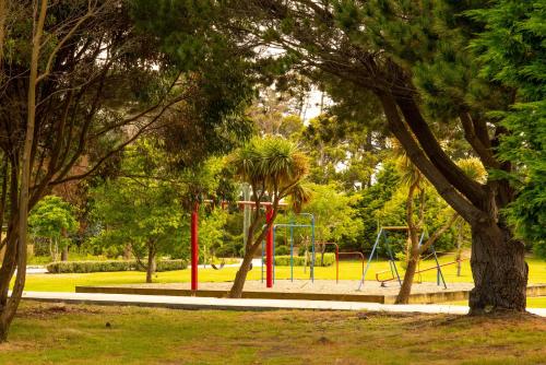 a park with a playground in the middle of a park at beach road holiday park in Otatara
