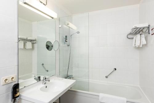 a white bathroom with a sink and a shower at ARVENA Kongress Hotel - Hotel in der Wagnerstadt in Bayreuth