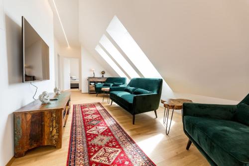 a living room with two green couches and a rug at Große Dachgeschosswohnung im Herzen von Graz in Graz