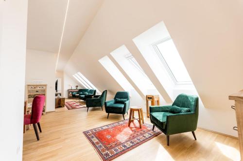 ein Wohnzimmer im Dachgeschoss mit grünen Stühlen und einem Teppich in der Unterkunft Große Dachgeschosswohnung im Herzen von Graz in Graz
