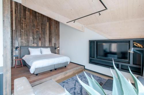 a bedroom with a bed and a flat screen tv at Waterrijk Oesterdam Hotel in Tholen