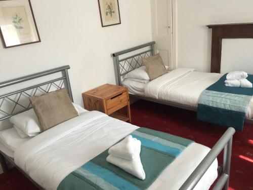 a room with two beds and a night stand with two beds at Sandpiper Guest House in Brighton & Hove