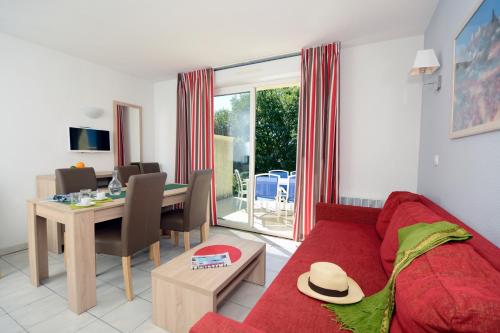 a living room with a red couch and a table at Résidence Odalys Les Hauts de Salavas in Salavas