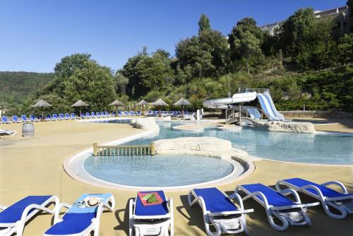 a swimming pool with lounge chairs and a water slide at Résidence Odalys Les Hauts de Salavas in Salavas