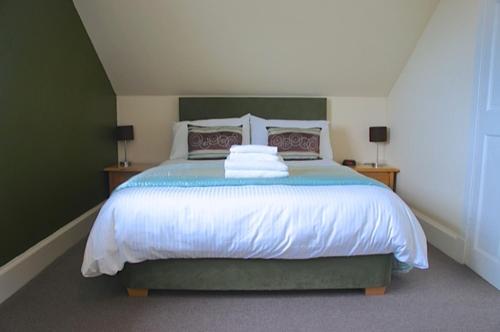 a bedroom with a large bed with green walls at Rooms by No2 Troon Road in Troon