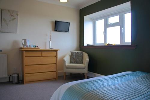 a bedroom with a bed and a chair and a dresser at Rooms by No2 Troon Road in Troon