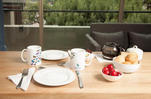 a wooden table with plates and utensils on it at Hotel Viaggio Teleport City Suites in Bogotá