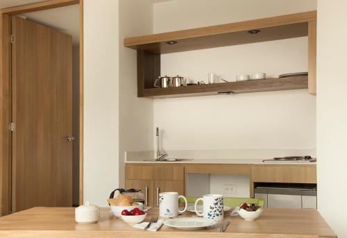 a kitchen with a table with cups and bowls on it at Hotel Viaggio Teleport City Suites in Bogotá