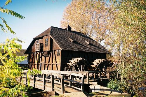 un antiguo granero de madera con un puente de madera en Vizimalom Kemping, Panzió és Étterem, en Túristvándi