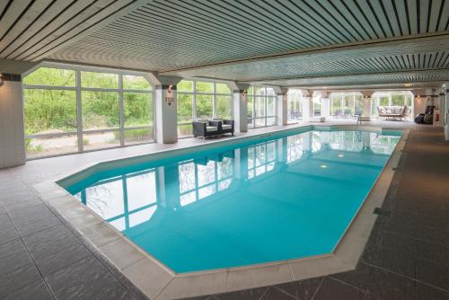 a swimming pool with a pool table and chairs at Fletcher Hotel Landgoed Avegoor in Ellecom