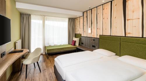 a bedroom with two beds and a desk and a television at Sporthotel Obereggen in Obereggen