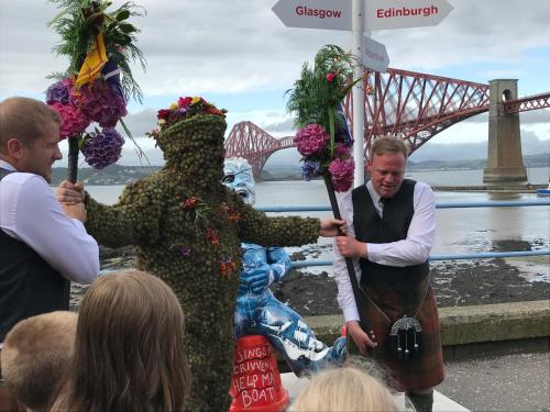 Um homem vestido de "auana" parado na frente de uma multidão. em Forth Reflections Self Catering em Queensferry