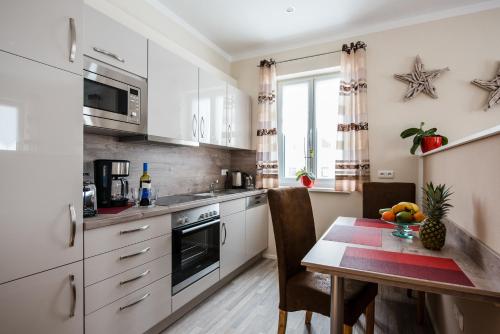 a kitchen with white cabinets and a dining table at Ferienwohnung/Businessapartment in Wolframs-Eschenbach