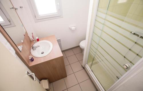 La salle de bains est pourvue d'un lavabo et d'une douche. dans l'établissement Résidence Odalys Le Village des Amareyeurs, au Château-dʼOléron
