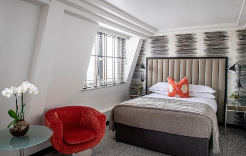 a bedroom with a bed and a red chair at The Marylebone Hotel in London