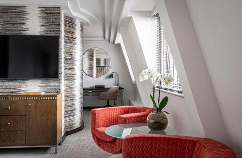 a living room with two red chairs and a tv at The Marylebone Hotel in London