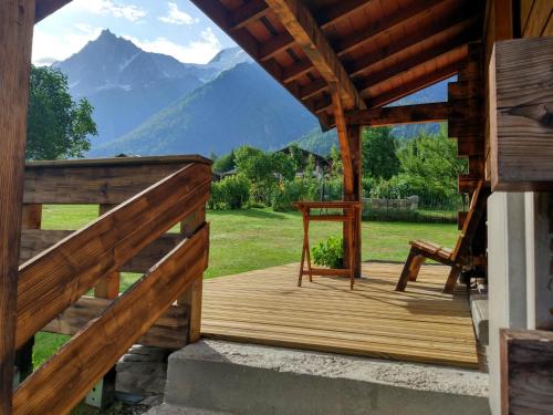 una terraza de madera con una silla y montañas en el fondo en Chalet Le Marmouzet, en Les Houches