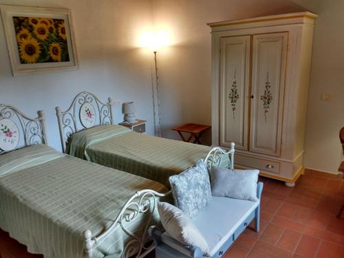 a bedroom with two beds and a chair and a cabinet at Casale I Burroni in Arezzo