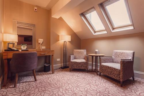 a room with two chairs and a desk and a window at The Gardens Hotel in Manchester