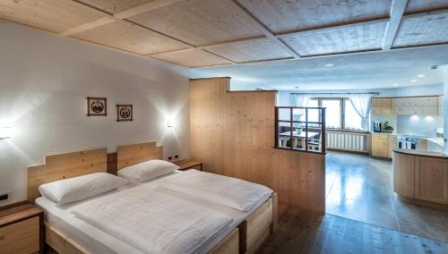a bedroom with a large bed and a kitchen at Ciasa Roenn in Colfosco