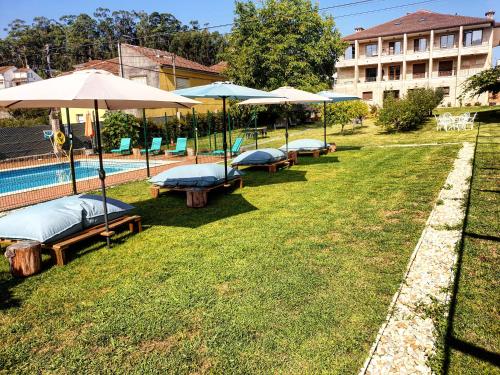 a row of benches with umbrellas next to a pool at Apartamentos Ria de Aldan in Aldán