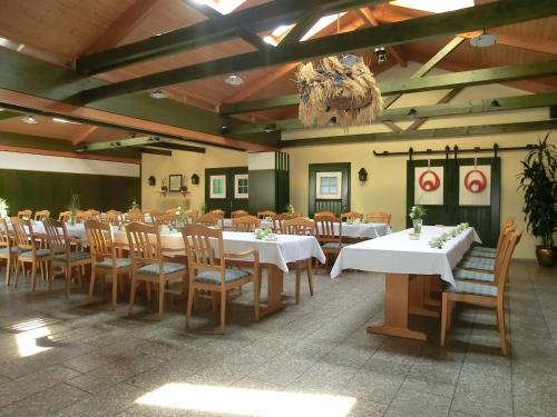 une salle à manger avec des tables blanches et des chaises en bois dans l'établissement Landhotel Wieseneck, à Winterfeld