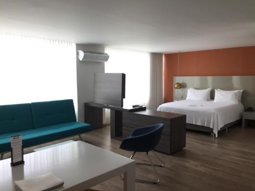 ein Schlafzimmer mit einem Bett, einem Schreibtisch und einem Sofa in der Unterkunft Hotel Holiday Inn Express & Suites Medellin, an IHG Hotel in Medellín