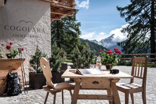 a wooden table and chairs on a patio with mountains at Ciasa Roenn in Colfosco