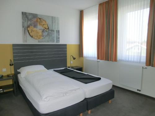a bedroom with a large bed with white sheets at Landhotel Wieseneck in Winterfeld