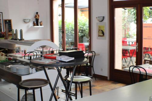 une cuisine avec une table et des chaises ainsi qu'une fenêtre dans l'établissement Hôtel Les Vignes Rouges, à Ispagnac