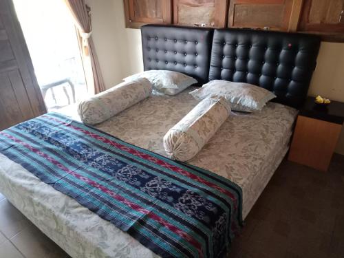 uma cama com cabeceira preta e almofadas em JOGLOPARI GuestHouse bukan untuk pasangan non pasutri em Bantul