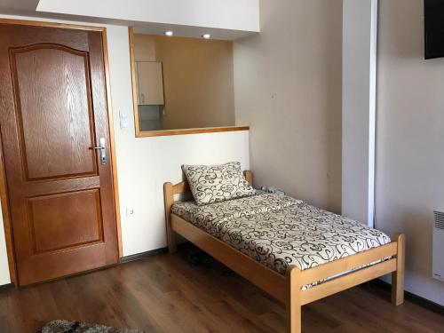 een kleine slaapkamer met een bed en een spiegel bij Vila Zlatarka Nova Varos in Nova Varoš
