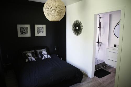 a bedroom with a black bed with two people on it at La maison d à côté in Lacropte