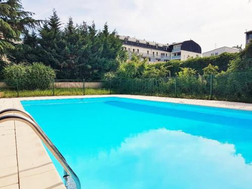 une grande piscine bleue devant un immeuble dans l'établissement Hortensias, à Toulouse