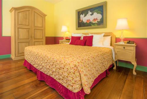 a bedroom with a bed and a dresser at Hotel Casa Turire in Turrialba